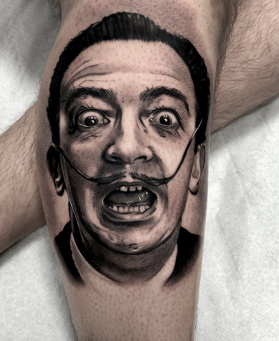 Tatuaje realista del rostro expresivo de Salvador Dalí