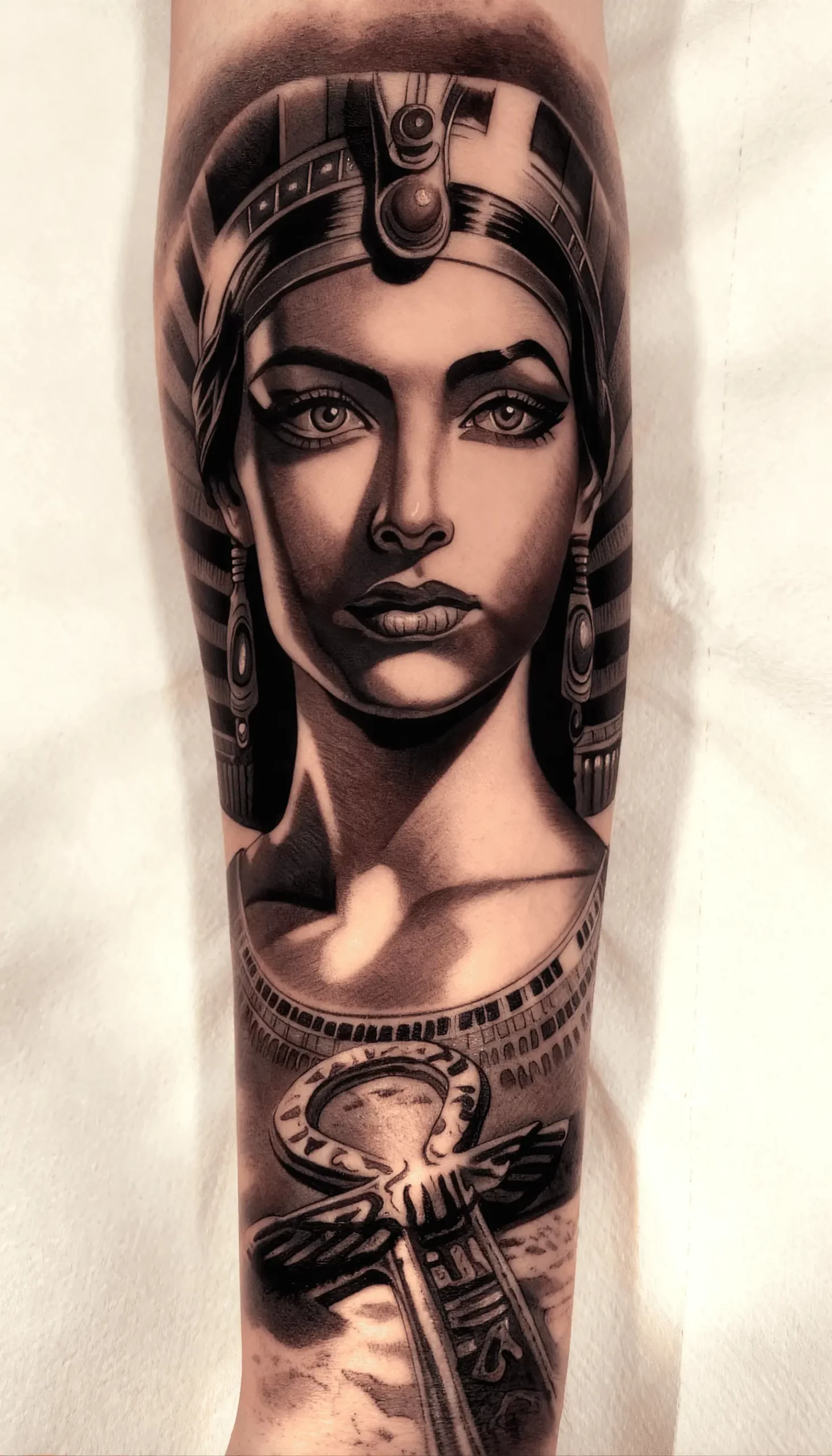 Tatuaje realista de mujer con tocado egipcio y símbolo anj